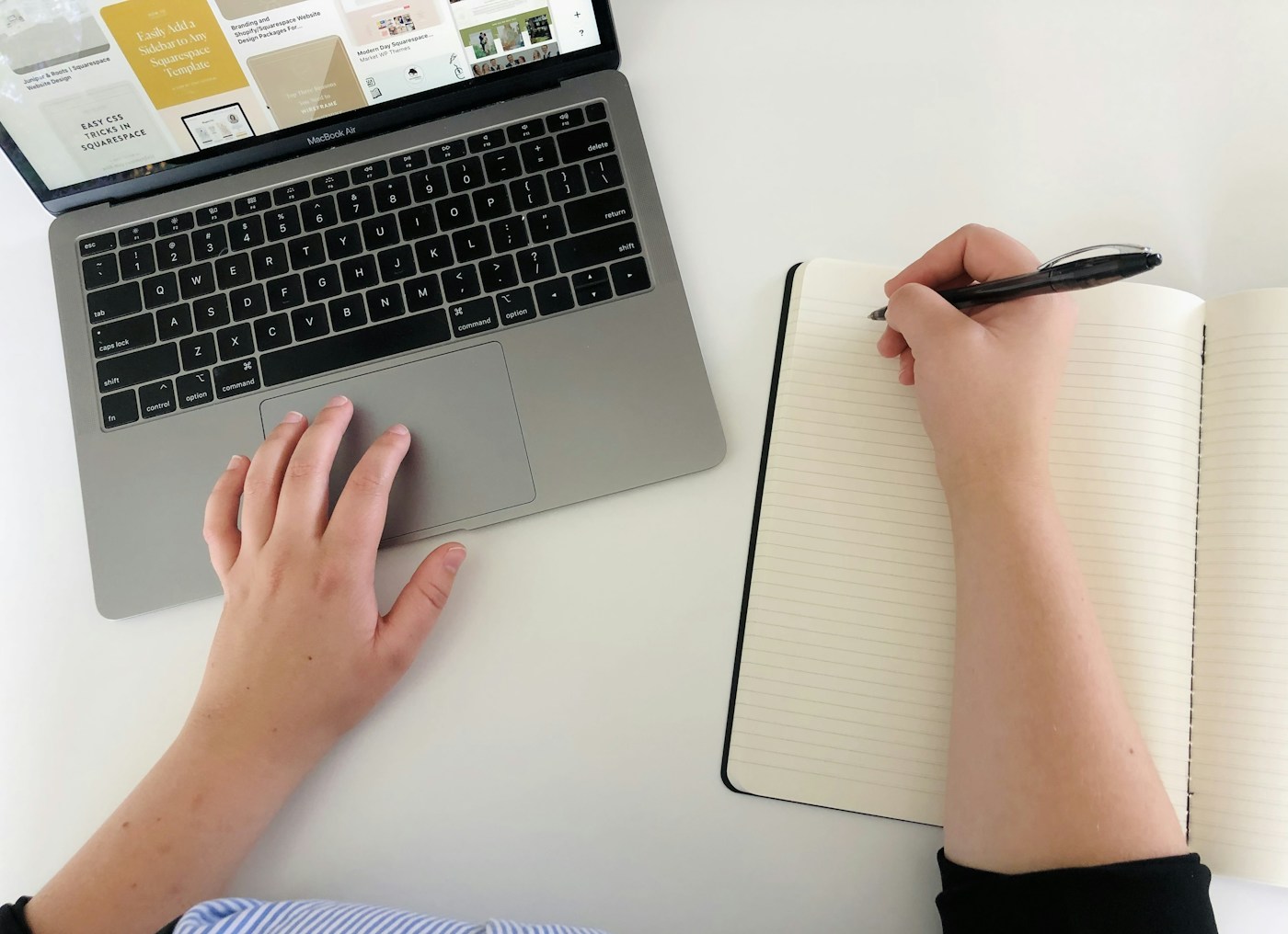 Una persona trabajando en un computador y organizando sus ideas en un cuaderno.